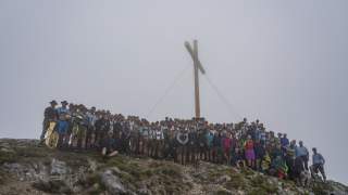 Die große Gruppe der Helfenden steht vor dem aufgestellten neuen Gipfelkreuz.