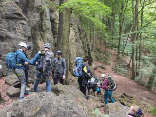 Eine Gruppe von Kletterer steigt über Felsen abwärts. Einige werden an der Hand geführt.