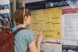 Frau studiert Fahrplan an Bahninformation