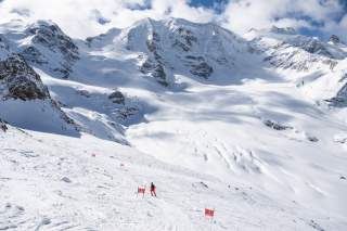 Ein Skifahrer bei einem Rennen auf einer naturbelassenen Gletscherpiste in den Alpen.