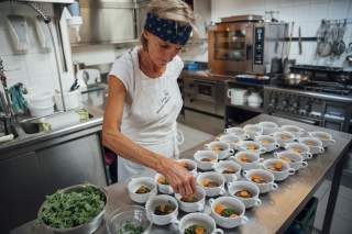 Köchin bereitet Suppenschüsseln in Hüttenküche vor