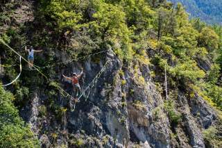 Zwei Menschen balancieren auf zwei Slacklines parallel über den Abgrund.