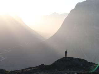 Mann steht auf Berg mit Aussicht auf weites Tal