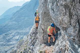 Drei Menschen im Klettersteig in felsiger Gebirgslandschaft