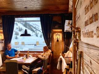 Zwei Menschen sitzen in gemütlicher Gaststube, vor dem Fenster liegt Schnee