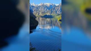 Zwei Boote fahren über den stillen Königssee vor der Kulisse der Berchtesgadener Alpen.