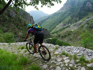 Mountainbiker fährt eine altertümlich gepflasterte Straße im Gebirge hinab.