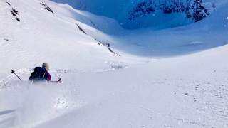 Mensch fährt tiefverschneiten Hang mit Ski hinab