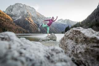 Frau macht Yoga an Bergsee