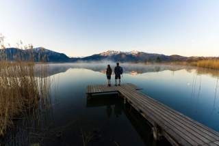 Zwei Menschen stehen auf Steg im See